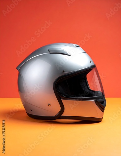 Silver motorcycle helmet on orange background
