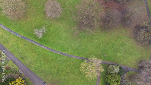 Overhead view of a park with winding paved paths, scattered trees, and open grassy areas, capturing a peaceful urban green space.