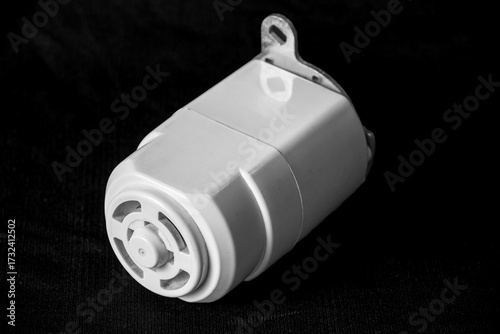 Close-Up of a White Electric Motor Used in Sewing Machine Isolated on Black Surface
