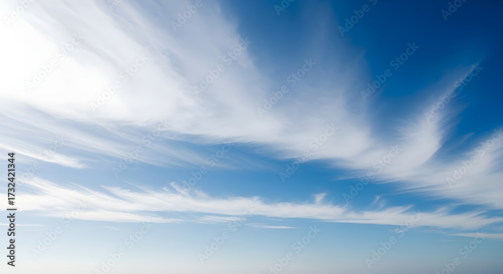 Fototapeta premium Wispy clouds paint the vast blue sky with ethereal beauty