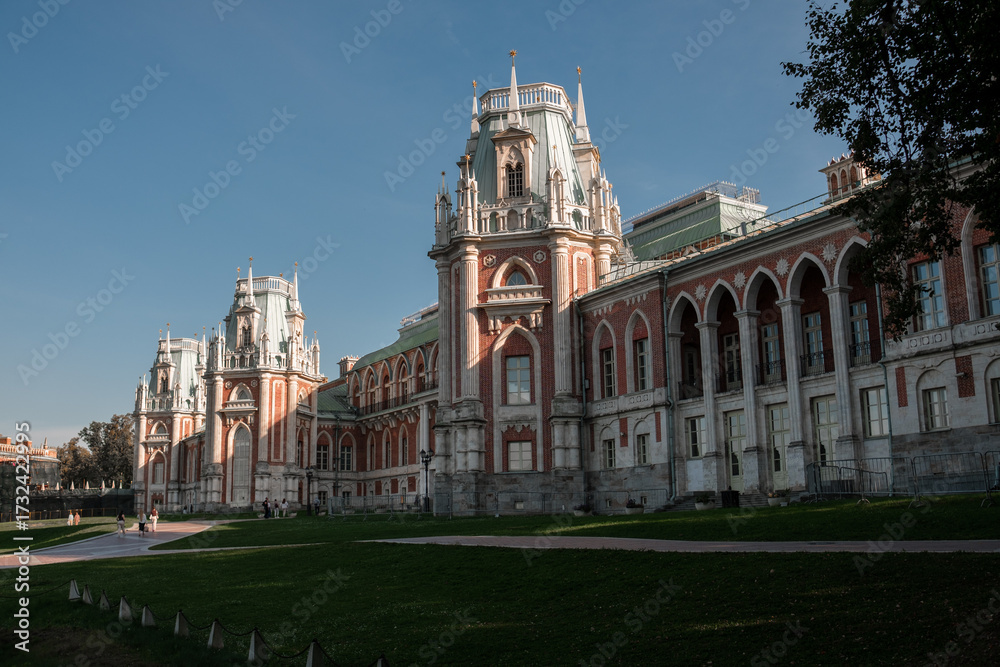 Obraz premium Visitors enjoy the serene beauty of Tsaritsyno park, admiring its impressive buildings and lush greenery under a bright blue sky