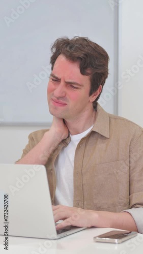Vertical Video, Young Man having Neck Pain while Working on Laptop