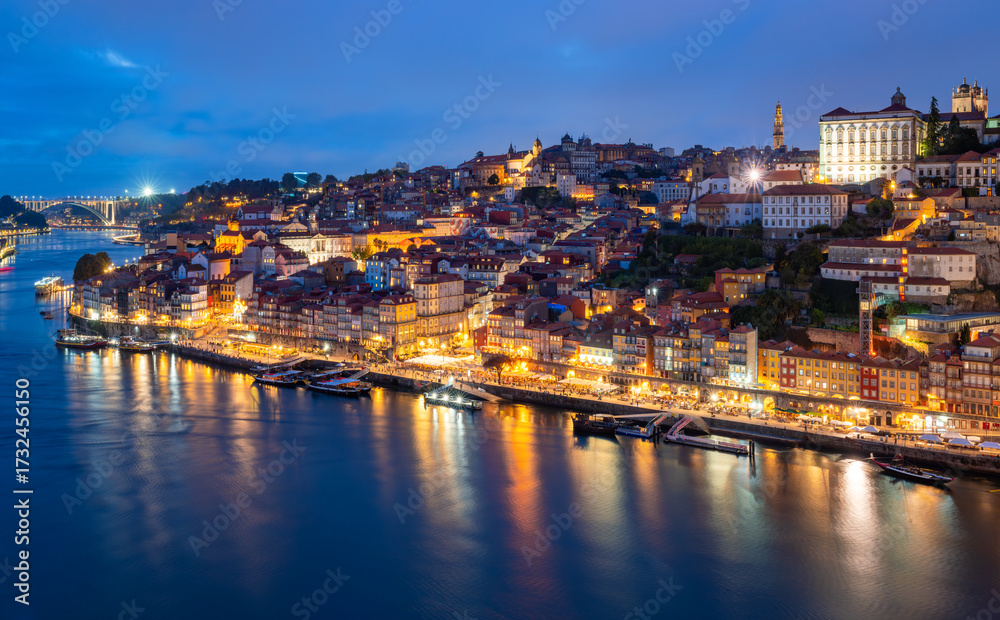 Fototapeta premium Panorama of the famous old town of Porto (Portugal) on the banks of the Douro River during the blue hour, with countless colourful lights seen from a popular sundowner viewpoint