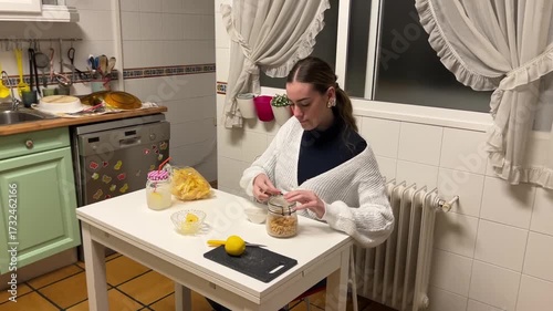 Teen girl closing a jar of peanuts and sealing a bag of potato chips after preparing a snack at the kitchen table