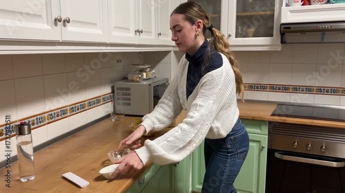 Teen girl setting potato chips and peanuts on the kitchen table to prepare a casual snack