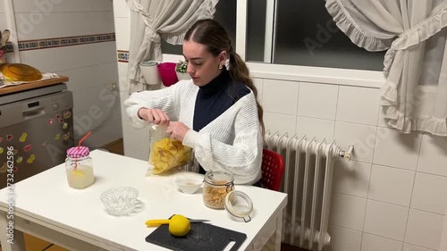 Teen girl opening a bag of potato chips at the kitchen table to prepare a snack