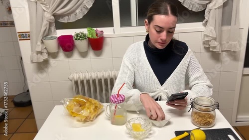 Teen girl sitting at the kitchen table focused on her phone during a quiet moment at home