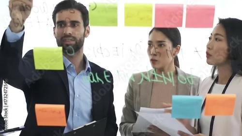 Business team working with sticky notes on glass wall brainstorming session