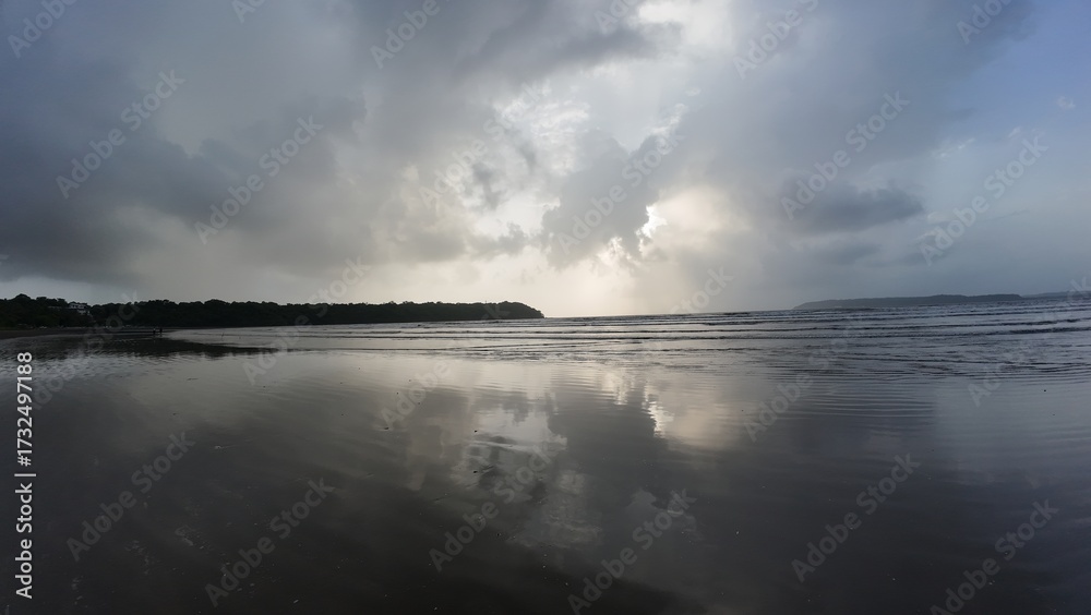 Fototapeta premium Serene Coastal Sunset with Cloud Reflections on Wet Sand Beach