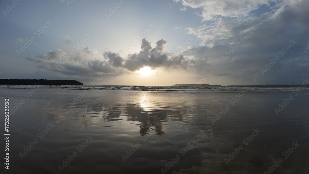 Obraz premium Tranquil Coastal Scenery: Rhythmic Movement of the Water and Symmetrical Reflections During the Golden Hour on a Broad, Flat Beach.