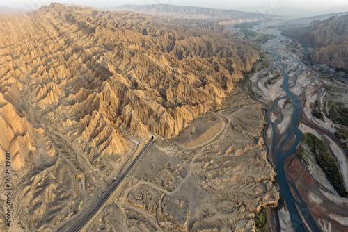 Aerial view of a ribbon of road and a tunnel cut through the geological wonders near a braided river, ÃœrÃ¼mqi, Xinjiang, China.