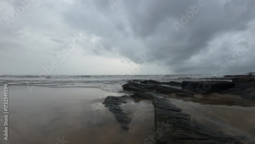 Moody and tranquil landscape of an evening beach, with a rocky shore and calm, misty ocean.