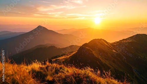 Fototapeta Naklejka Na Ścianę i Meble -  A golden sunset bathes a mountain range in warm light, with layers of peaks fading into a hazy horizon