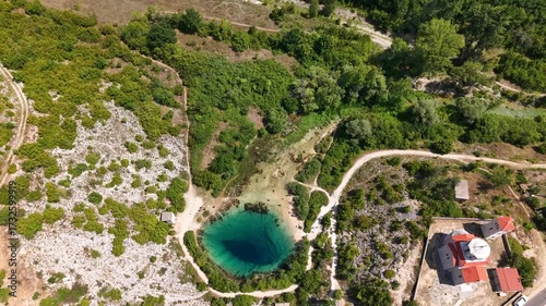 Breathtaking aerial footage of a vibrant turquoise karstic spring Cetina River spring, Izvor Cetine nestled amidst lush green and rocky terrain, nature's unique geological wonders eye of the Earth