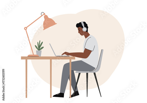 Focused individual working on laptop at desk with lamp and plant in cozy home office environment