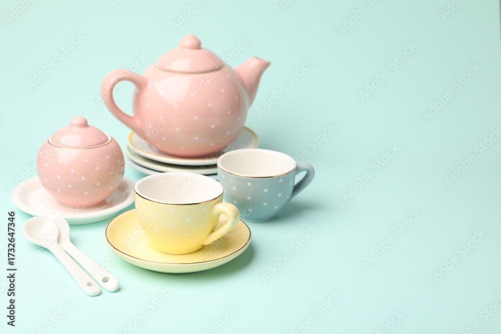 Fototapeta premium Beautiful ceramic tea set for children on turquoise background. Space for text