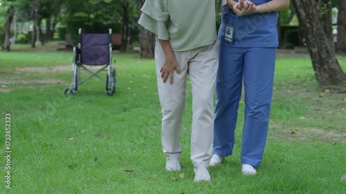 The caregiver is helping an elderly Asian woman rehabilitate her walking and monitor her condition after she underwent knee surgery, using treatment information from her doctor.