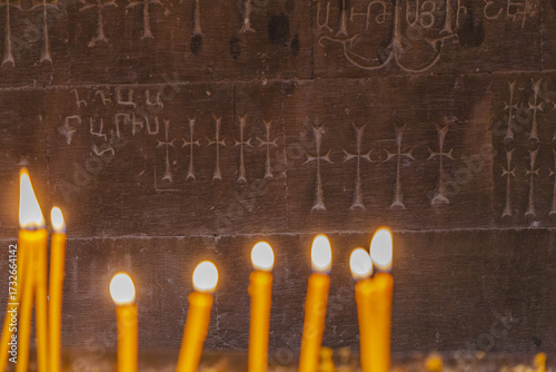 View of flickering candlelight dances against the ancient stone, illuminating carved crosses and Armenian script, creating a warm glow in Noravank Monastery, Vayots Dzor Province, Armenia.