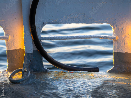 Photography Close-Up of Boat Railing with Hose and Water Reflection