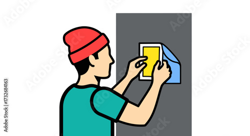 Young man in a red beanie carefully applying a sticker.