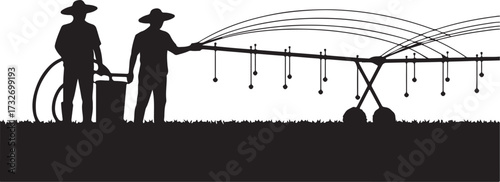 Two farmers in silhouette operating a water irrigation system on a grassy field agriculture farming