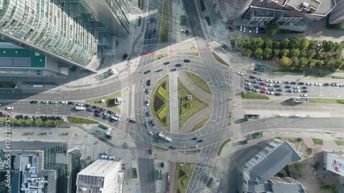 Aerial drone pull-up over ONZ Roundabout in Warsaw with city traffic and passing trams, Poland