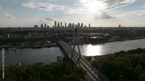 Aerial drone view of Świętokrzyski Bridge and Warsaw skyline at sunset with sunlight reflection on Vistula River, Poland