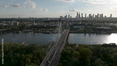 Aerial side fly-by of Świętokrzyski Bridge over Vistula River with Warsaw skyline in the background, Poland