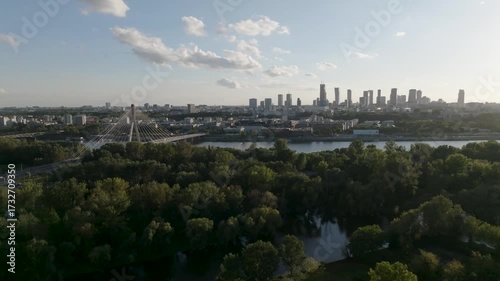 Aerial drone push-in towards Warsaw city skyline with bridges and green areas, Poland