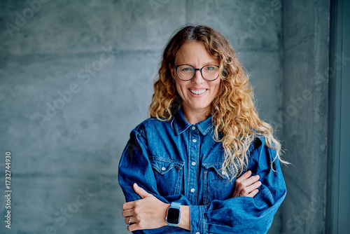 Obraz na plátne Professional woman with curly hair smiling and crossing arms, expressing confide
