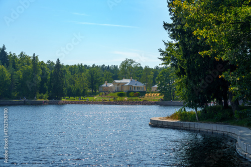 Historic manor house by calm forest lake on a sunny summer day