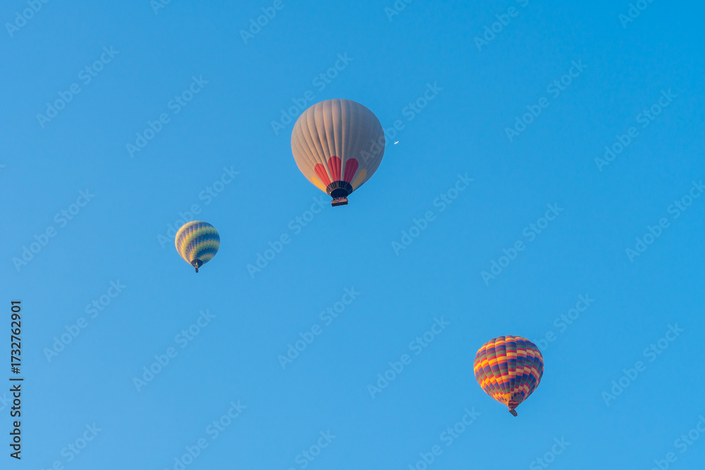 Obraz premium Three hot air balloons against a blue sky. Beautiful view of colourful hot air balloons from below. Cappadocia