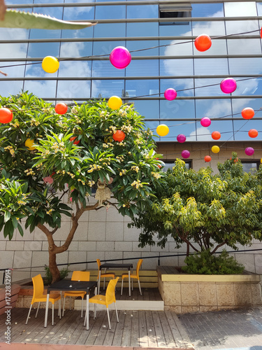 Haifa, Israel, 12 June 2025,  Vibrant Urban Patio with Floating Balloons and Glass Facade