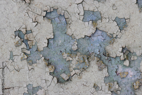 Peeling paint on the wall. Old concrete wall with cracked flaking paint. Weathered rough painted surface with patterns of cracks and peeling. High resolution texture for background and design. Closeup