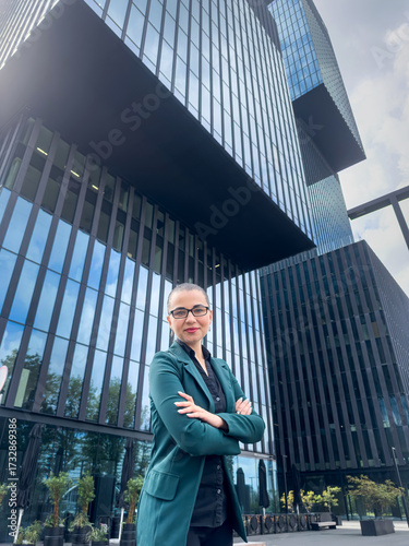 Portrait of confident  buisness woman in suit walk on street in city centre near glass skyscrapers