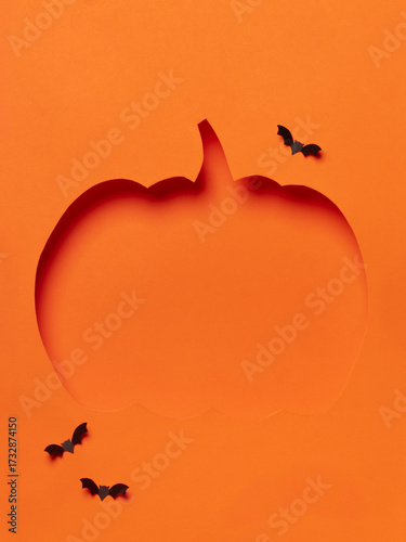 Orange pumpkin cutout with flying black bats.