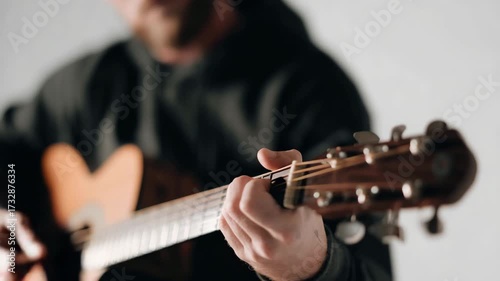 Musician plays acoustic guitar while focusing on strumming technique in a cozy indoor space