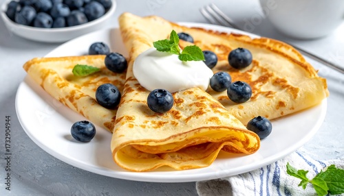 Golden crepes topped with blueberries and whipped cream (1)