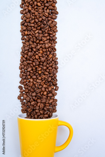 A yellow coffee cup is filled with coffee beans.