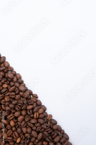 triangle of roasted coffee beans scattered on a white background