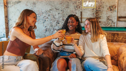 Foto Multiracial women friends enjoying a toast with fresh juice in a relaxed setting