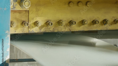 Close up view of a powerful hydraulic guillotine shearing machine cutting a large metal sheet in an industrial factory setting, demonstrating a precision manufacturing and metalworking process