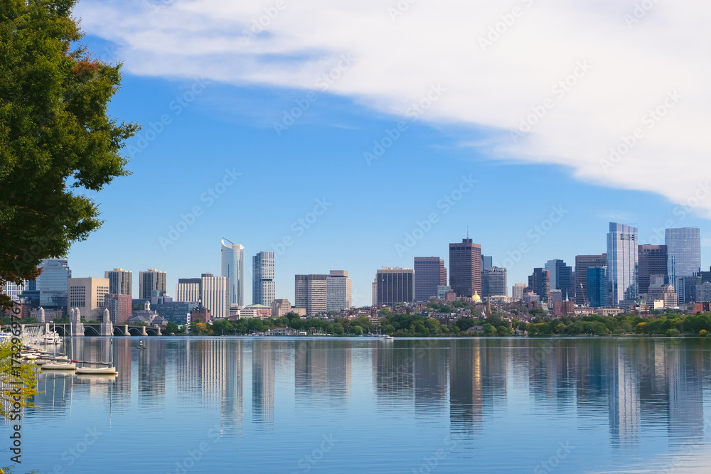 Obraz premium Boston skyline reflected in the calm waters of the Charles River under a bright blue sky, fall in american cities