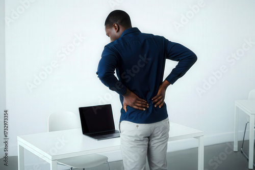 Medical Illnesses and Ailments – Black middle-aged man holding his lower back, suffering from chronic or acute lumbar pain at work