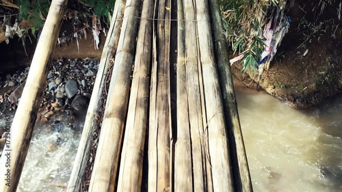 Navigating nature's path crossing a bamboo bridge over rushing water, a thrilling adventure across an old bridge and flowing river current