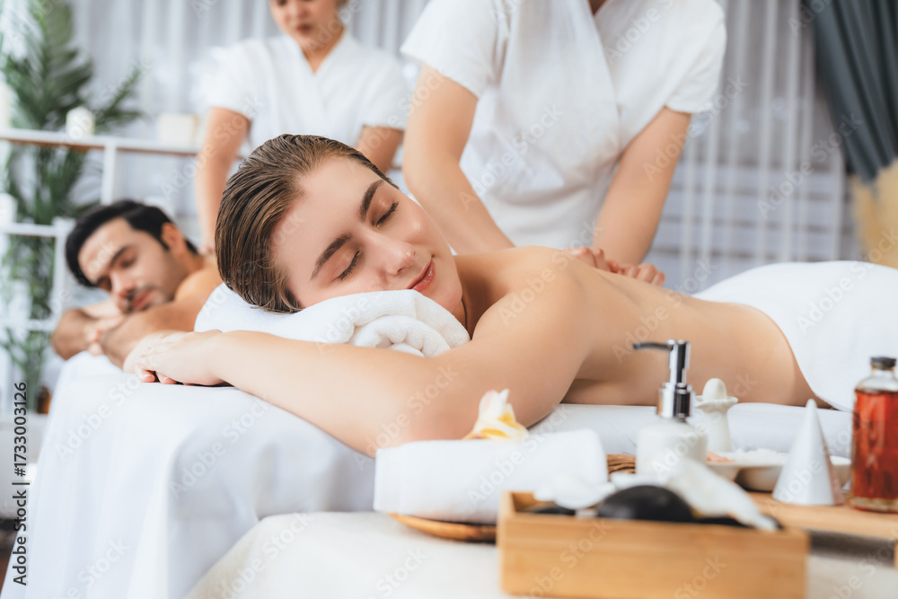 Obraz premium Caucasian couple customer enjoying relaxing anti-stress spa massage and pampering with beauty skin recreation leisure in day light ambient salon spa at luxury resort or hotel. Quiescent