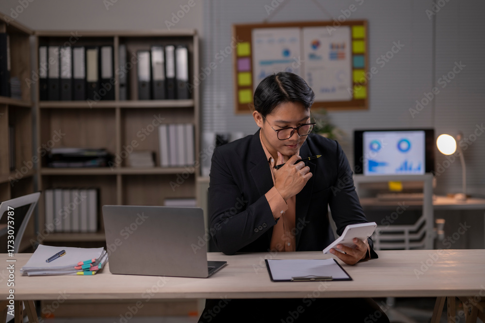 Fototapeta premium A man in a suit is sitting at a desk with a laptop and a tablet