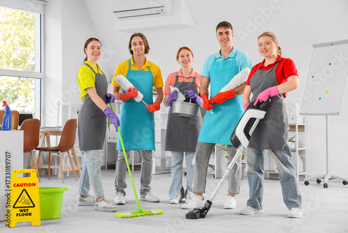 Team of janitors with cleaning supplies in office