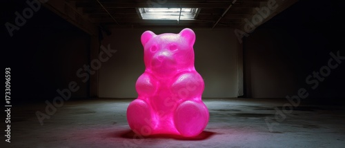 A large, glowing pink gummy bear sculpture stands in an empty room, creating a whimsical and surreal atmosphere.