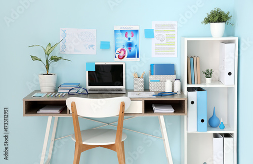 Medical student's workplace with blank laptop and study materials near blue w...